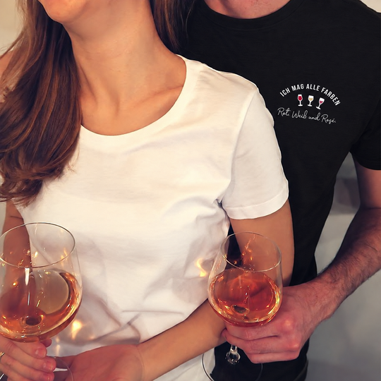 Digital bearbeitete eigene Paar-Trageansicht: Herren T-Shirt in Schwarz mit Ich mag alle Farben klein links auf der Brust; Begleitshirt in Weiß ohne Druck.