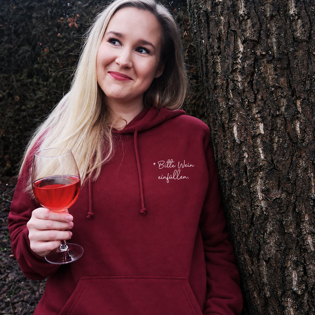 Bitte Wein einfüllen – Unisex-Hoodie in Bordeaux mit kleinem weißem Brustprint, draußen getragen