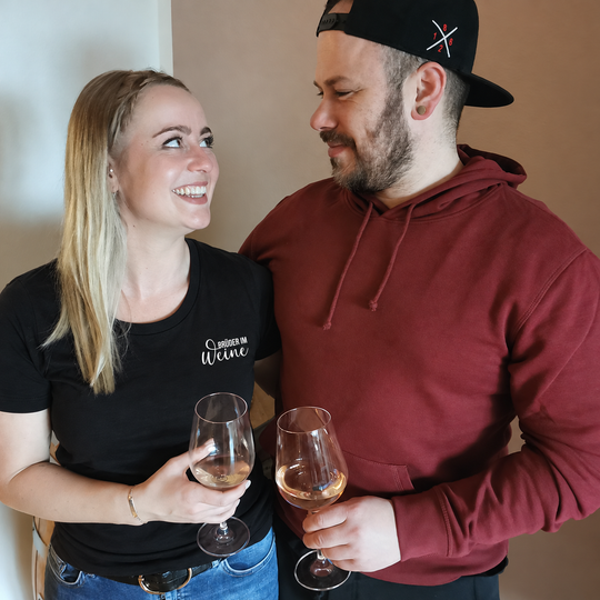 Tamara trägt das schwarze Brüder im Weine Damen-T-Shirt mit kleinem weißem Brustmotiv.