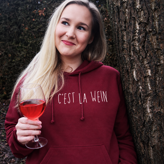 Digital bearbeitete eigene Trageaufnahme: C’est la Wein auf einem Bordeaux-Hoodie, weißes Motiv mittig auf der Brust