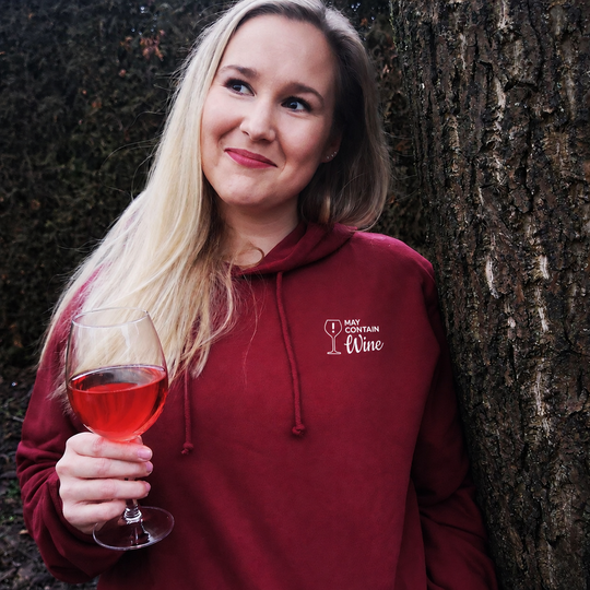 Tamara im Bordeaux May contain wine Hoodie mit kleinem Brustmotiv bei einem Glas Wein im Freien