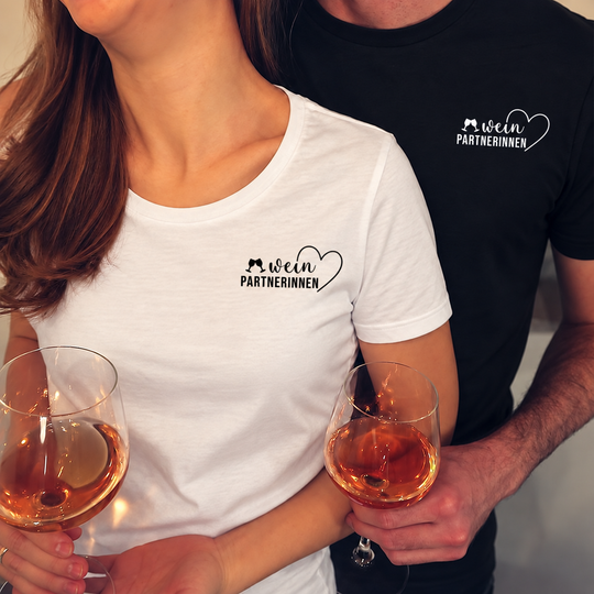 Digital bearbeitete Paaraufnahme mit Weinpartnerinnen-Motiv: Herren-Shirt schwarz mit weißem Druck, Damen-Shirt weiß mit schwarzem Druck; Shirts separat erhältlich.
