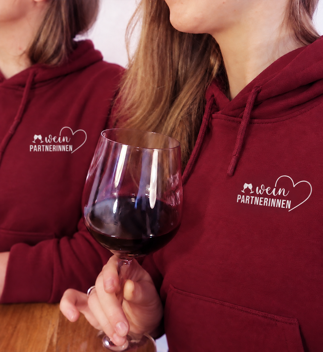 Digital bearbeitete Trageansicht zweier vorhandener Models in Bordeaux-Weinpartnerinnen-Hoodies mit weißem Gläser- und Herzmotiv; Hoodies einzeln erhältlich.